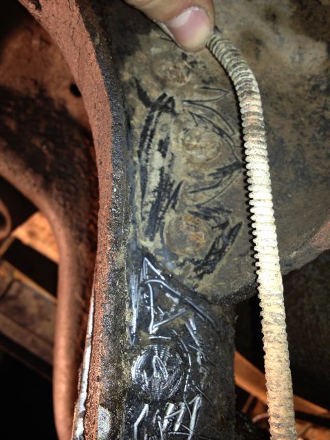 1995 Ford Bronco - Close-up of a rusty undercarriage component with white markings and a ribbed cable attached.