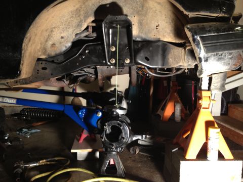 1995 Ford Bronco - Vehicle suspension components and frame are visible while supported by jack stands in a garage setting.