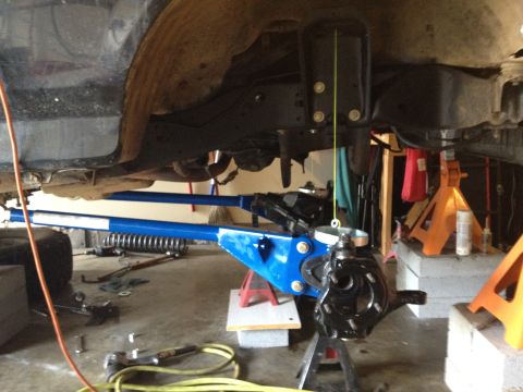 1995 Ford Bronco - The underside of a vehicle is shown with suspension parts being worked on, supported by jack stands.