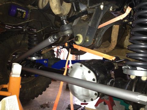 1995 Ford Bronco - Vehicle undercarriage showing suspension parts, differential, and tie rods, with orange straps securing components.