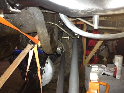 1995 Ford Bronco - Close-up view of a vehicle's undercarriage, showing suspension and axle components secured with straps.