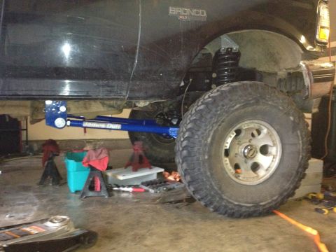 1995 Ford Bronco - A black Ford Bronco XLT is shown from the side, undergoing modifications with large tires and suspension work.