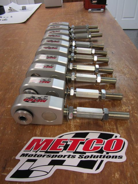 1992 Ford Crown Victoria - Several Metco Motorsports Solutions adjustable control arms are laid out on a wooden table, with the brand's logo sticker in the foreground.