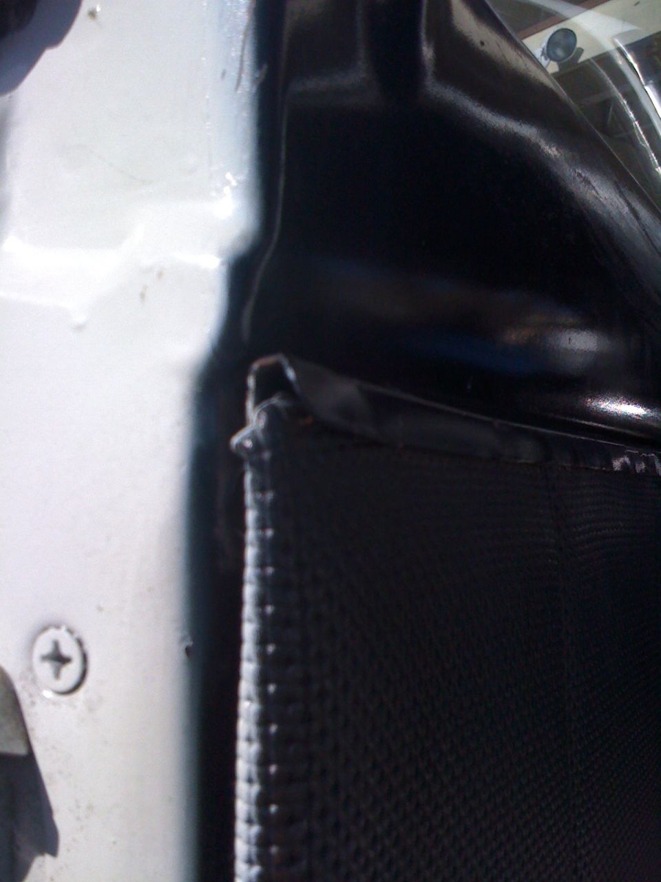 close-up of car door panel with black textured material and white painted metal