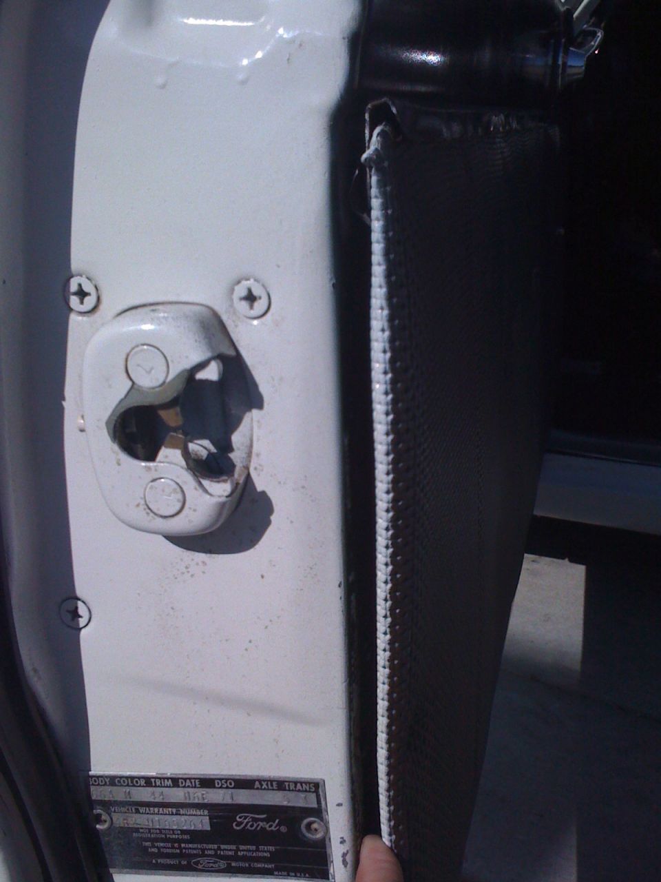 White door latch and trim panel with visible VIN plate on 1964 Ford Ranchero