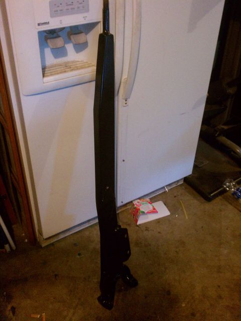 1992 Ford Bronco - Unidentified black metal part shown indoors, leaning against a refrigerator.
