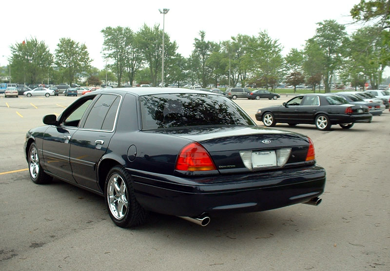 Dark blue Ford Crown Victoria rear three-quarter view with chrome wheels in a parking lot