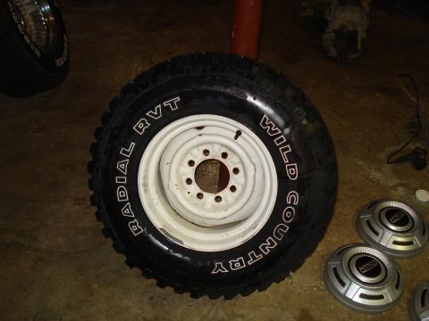 1967 Ford F-250 - A single tire and wheel assembly with white lettering is shown, alongside two hubcaps.
