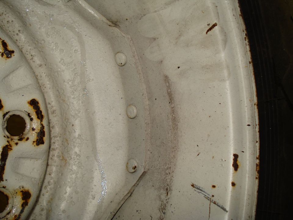 White wheel rim with rust spots and visible lug nut holes