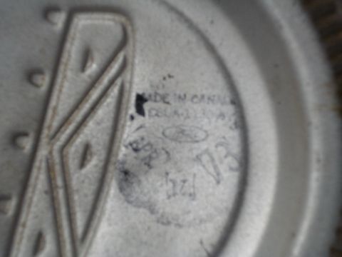1967 Ford F-250 - A close-up view of a stamped Ford emblem with "MADE IN CANADA" and a part number visible.