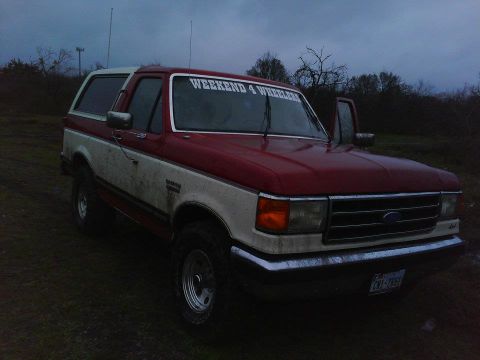 1989 Ford Bronco - This two-tone red and white 1989 Ford Bronco features a "WEEKEND 4 WHEELERS" decal on the windshield.