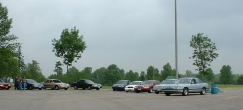 2000 Ford Crown Victoria - A light blue 2000 Ford Crown Victoria is parked in a lot with several other vehicles under a cloudy sky.