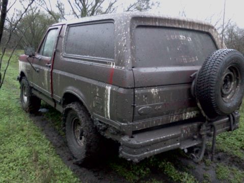 1989 Ford Bronco - This 1989 Ford Bronco is heavily covered in mud, showing its rear end and spare tire mounted on the tailgate.