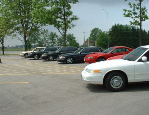 2000 Ford Crown Victoria - A white 2000 Ford Crown Victoria is parked in a lot with other vehicles.