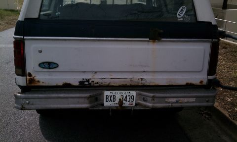 1984 Ford Bronco - This 1980s Ford Bronco shows significant rust damage on its rear panel and bumper.