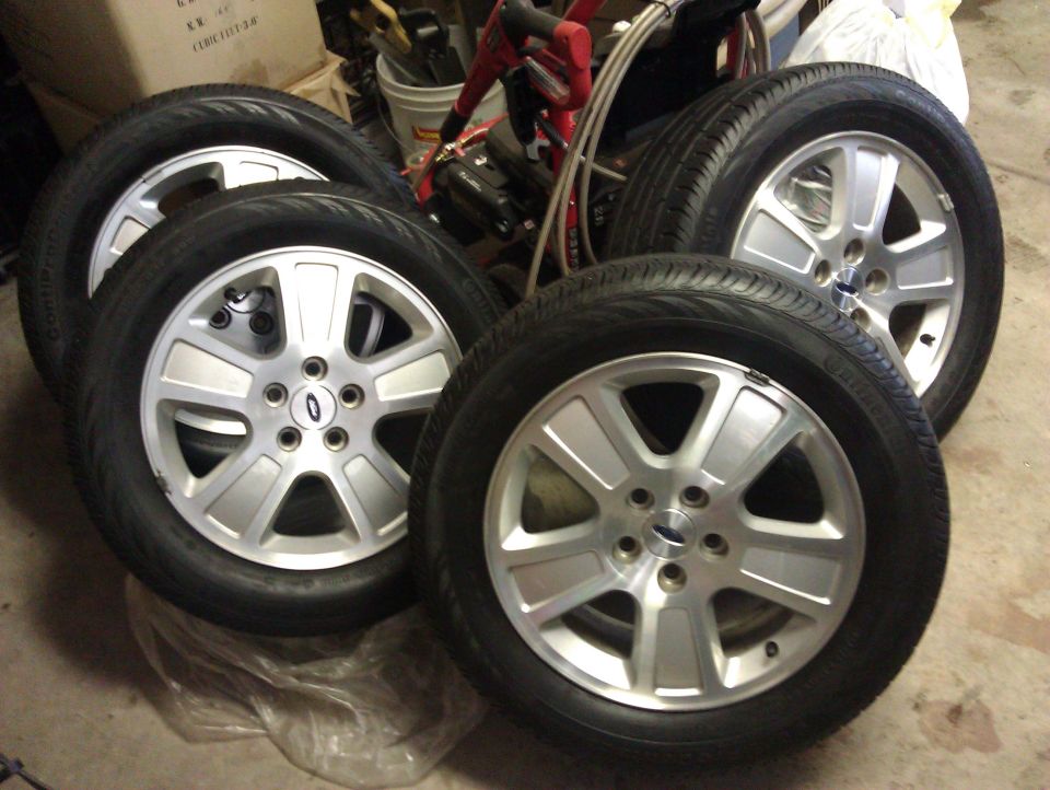 Four silver alloy wheels with tires, each with a Ford logo in the center