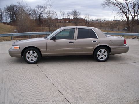 2007 Ford Crown Victoria - Side profile of a tan 2007 Ford Crown Victoria sedan parked on a concrete surface.