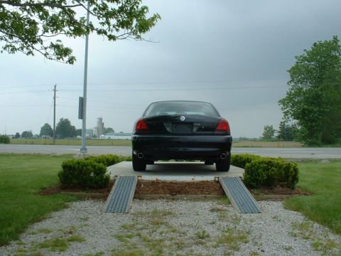 2000 Ford Crown Victoria - Rear view of a black sedan on a raised platform, with ramps leading up to it.