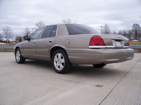 2007 Ford Crown Victoria - Rear view of a tan 2007 Ford Crown Victoria sedan parked outdoors on a cloudy day.