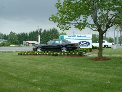 2000 Ford Crown Victoria - A black 2000 Ford Crown Victoria is displayed on a lawn in front of a Ford dealership sign.