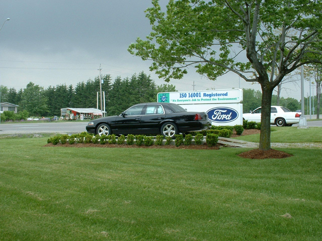 Black 2000 Ford Crown Victoria parked on grass, side view. White Ford Crown Victoria in background