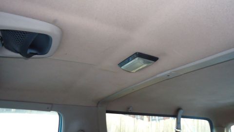 1996 Ford Bronco - The interior ceiling of a vehicle is visible, an air vent and a dome light.