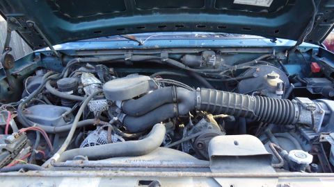 1996 Ford Bronco - Engine bay of a 1996 Ford Bronco, showing hoses, air intake, and other engine components.