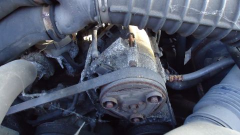 1996 Ford Bronco - Close-up view of a vehicle's engine compressor and drive belt, showing signs of wear and corrosion.