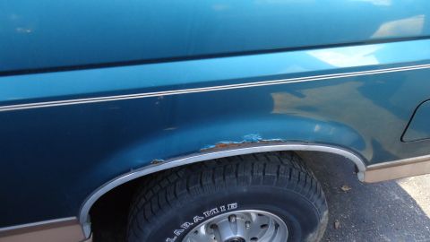 1996 Ford Bronco - Close-up of the rear fender and wheel well on a 1996 Ford Bronco, showing rust damage.