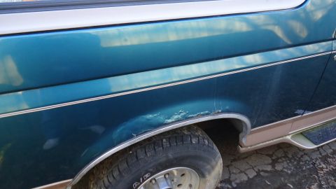 1996 Ford Bronco - Close-up of the side of a teal SUV, showing the fender, wheel, and trim details.