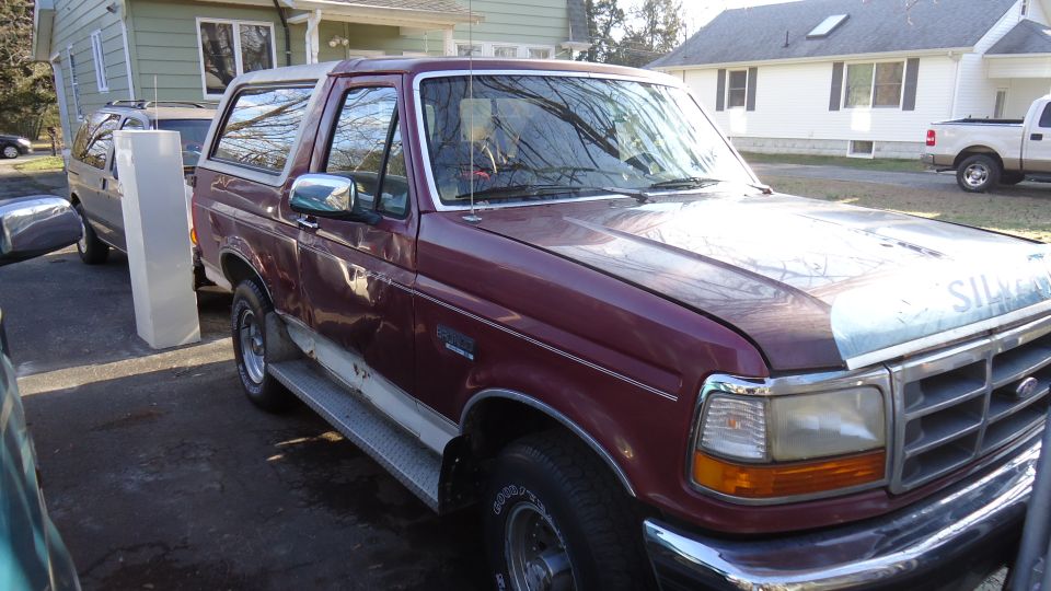 Maroon 1996 Ford Bronco parked next to a gray SUV