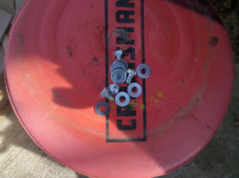 1979 Ford Bronco - A collection of fasteners is laid out on a red surface, possibly a tool chest lid.