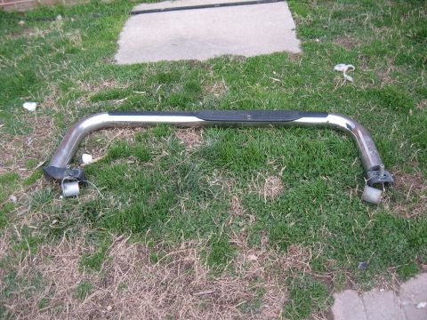 1994 Ford Bronco - A single chrome nerf bar with a black step pad is shown lying on the grass.