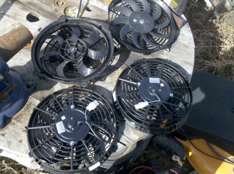 1979 Ford Bronco - Multiple electric cooling fans are displayed on a wooden surface, possibly for sale or installation.