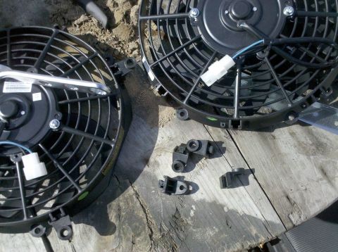 1979 Ford Bronco - Two electric fans and their mounting hardware are laid out on a wooden surface, possibly for installation.
