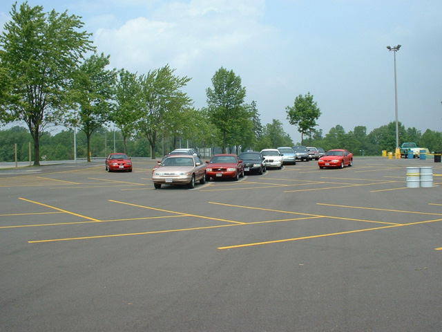 Parking lot with several cars including a 2000 Ford Crown Victoria, red Ford Mustang, and other sedans