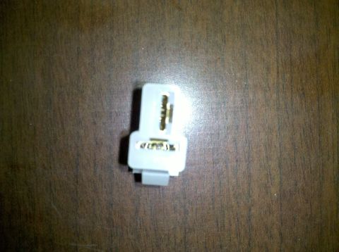 1979 Ford Bronco - A close-up view of a white electrical connector with visible gold terminals, set against a wooden background.