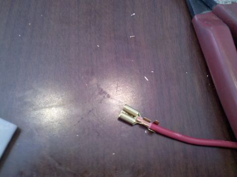 1979 Ford Bronco - A close-up shows a wire with a metal connector attached, next to a pair of pliers on a wooden table.