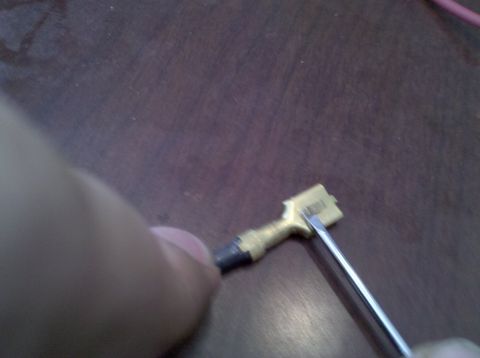 1979 Ford Bronco - A person is using a screwdriver to manipulate a gold-colored electrical connector with black tape on one end.