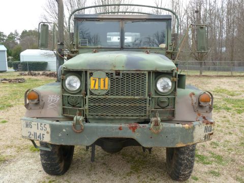 1992 Ford Mustang - This military truck has a camouflage paint scheme and various markings on its front.