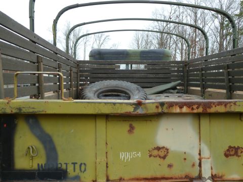 1992 Ford Mustang - The rear of a utilitarian truck shows signs of age and use, with visible markings on its olive drab exterior.