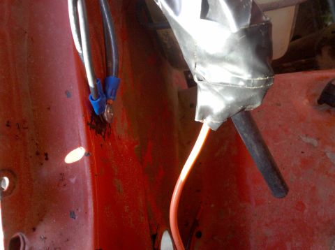 1979 Ford Bronco - This image shows a close-up of electrical wiring connections and tape on a red surface, likely part of a vehicle's engine bay.