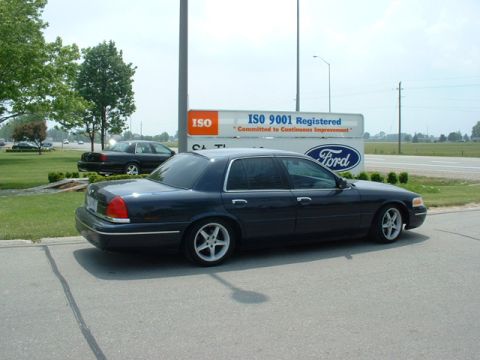 2000 Ford Crown Victoria - Two Ford Crown Victorias are visible, one in the foreground and another in the background.