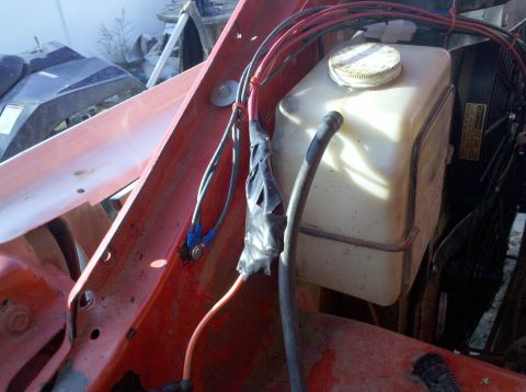 1979 Ford Bronco - Close-up of engine bay wiring and a plastic fluid reservoir, with a "CAUTION" label on a fan shroud.