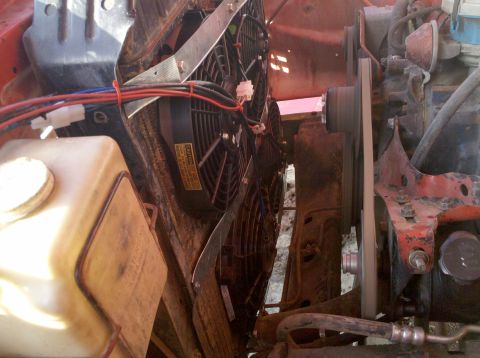 1979 Ford Bronco - Close-up view of electric fans installed in front of a radiator, with associated wiring and a coolant overflow tank.