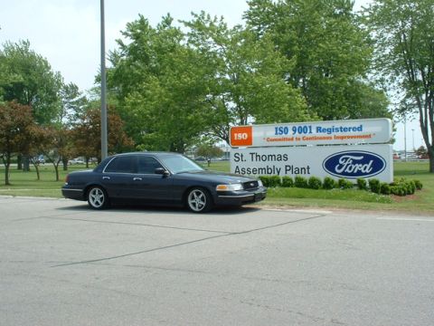 2000 Ford Crown Victoria - A dark blue 2000 Ford Crown Victoria is parked in front of the St. Thomas Assembly Plant sign.