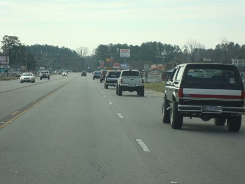 1995 Ford Bronco - A line of vehicles travels down a highway on an overcast day.