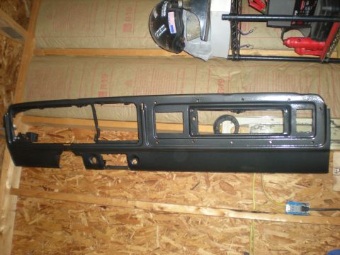 1978 Ford Bronco - A black dashboard panel is mounted on a wooden wall, showing openings for instruments and controls.
