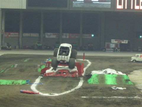 1986 Ford Bronco - A monster truck is positioned on top of several crushed cars in an arena.