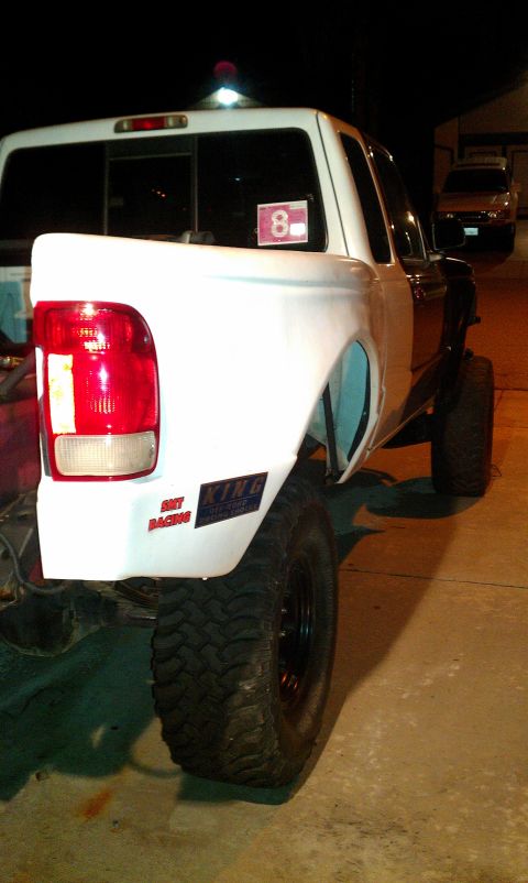 1992 Ford Ranger - A white pickup truck is shown from the rear quarter, large off-road tires and a sticker with the number 8 on the rear window.